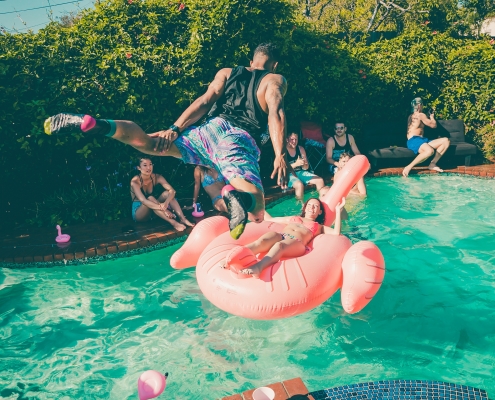 A dude diving into a pool at a party.