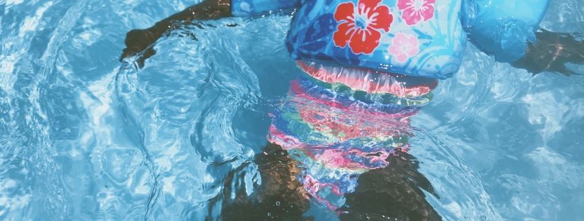 toddler wearing blue floral pool float on swimming pool